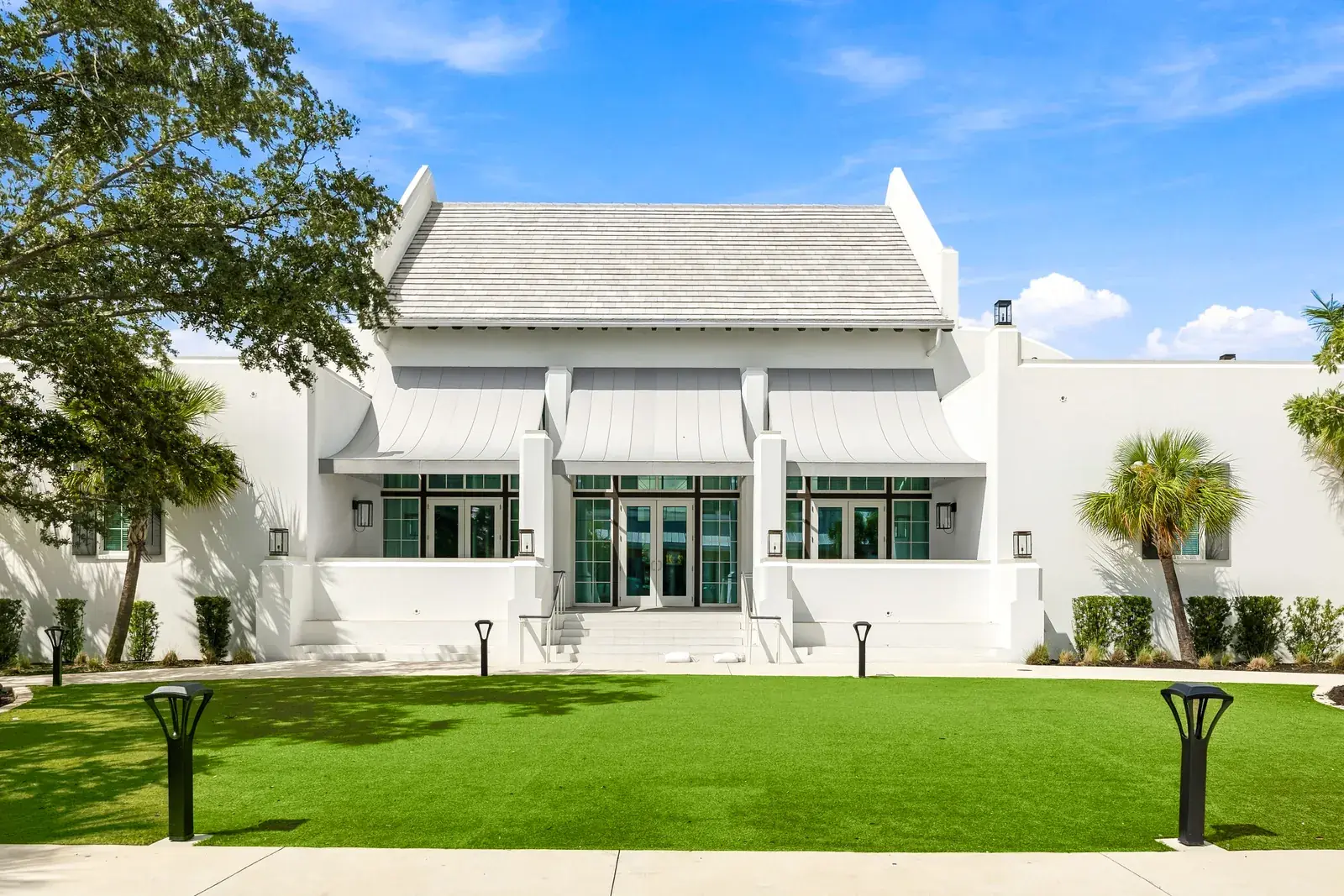 White gabled hall with green doors facing a mowed lawn in downtown Wellen Park